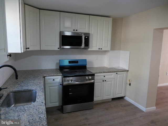 kitchen with white cabinets, light hardwood / wood-style floors, sink, and appliances with stainless steel finishes