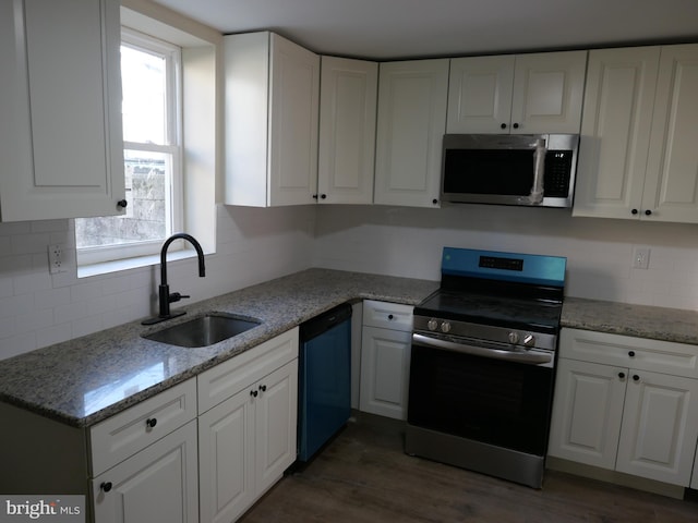 kitchen featuring light stone counters, stainless steel appliances, sink, white cabinets, and dark wood-type flooring