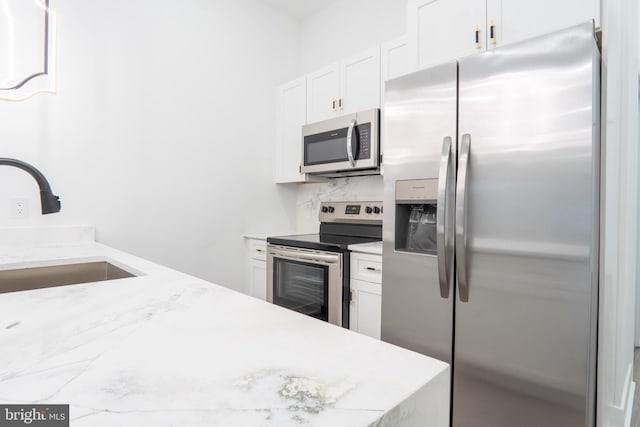 kitchen featuring stainless steel appliances, white cabinets, sink, backsplash, and light stone countertops