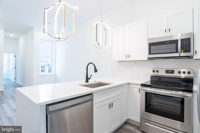 kitchen with white cabinets, stainless steel appliances, hanging light fixtures, and sink