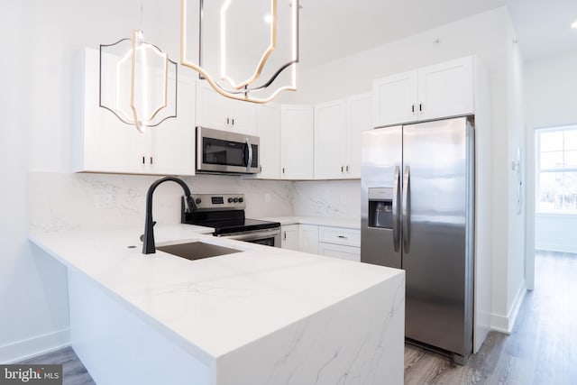 kitchen featuring stainless steel appliances, white cabinetry, backsplash, hanging light fixtures, and kitchen peninsula