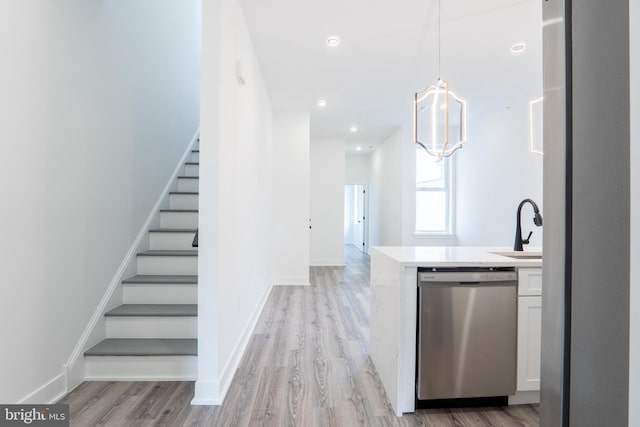 kitchen featuring dishwasher, hanging light fixtures, light hardwood / wood-style floors, and white cabinets