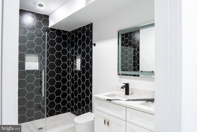 bathroom with tiled shower, vanity, and toilet