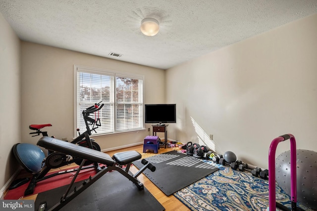 workout room with wood-type flooring and a textured ceiling