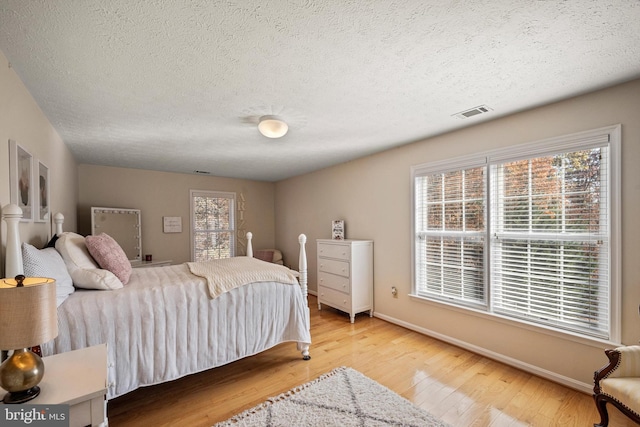 bedroom with a textured ceiling and light hardwood / wood-style flooring