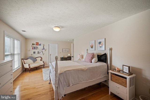 bedroom with a textured ceiling and light hardwood / wood-style floors