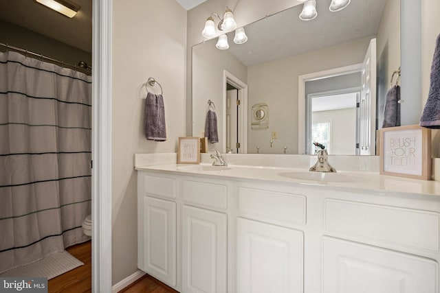 bathroom with hardwood / wood-style flooring, a textured ceiling, curtained shower, vanity, and toilet