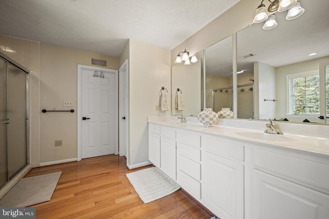 bathroom with hardwood / wood-style floors, walk in shower, a textured ceiling, and vanity