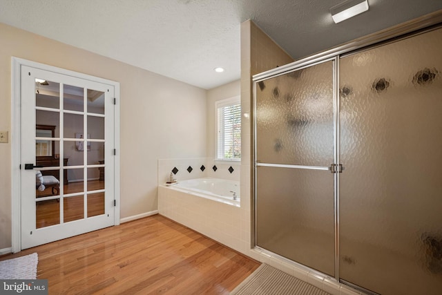 bathroom featuring shower with separate bathtub, wood-type flooring, and a textured ceiling