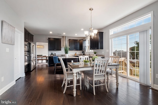 dining area with a wealth of natural light, a notable chandelier, and dark hardwood / wood-style floors