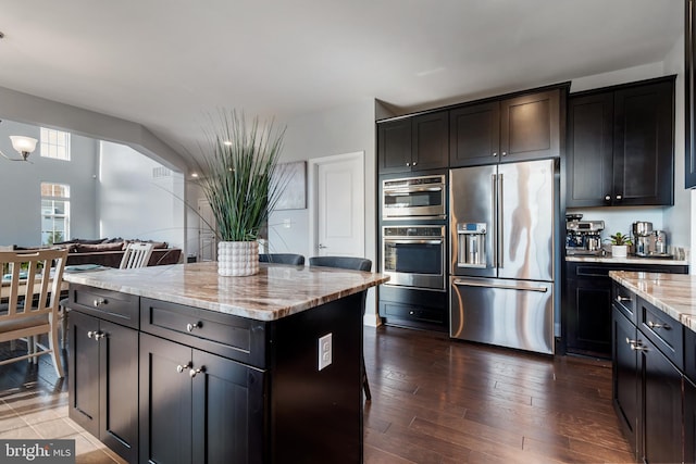 kitchen with a kitchen island, light stone countertops, dark hardwood / wood-style floors, and stainless steel appliances