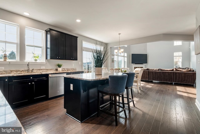 kitchen featuring sink, a kitchen breakfast bar, a kitchen island, dishwasher, and dark hardwood / wood-style flooring