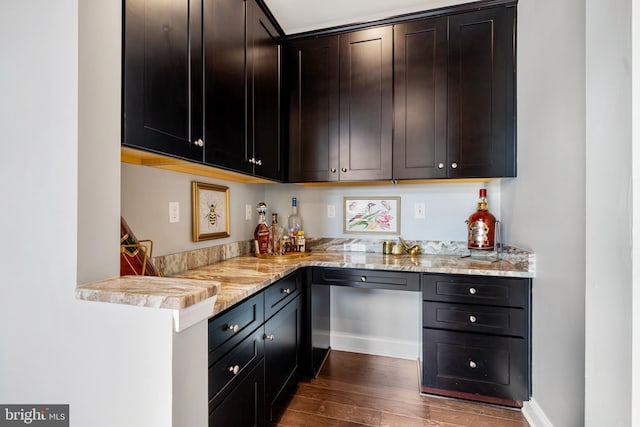 kitchen with dark wood-type flooring, light stone countertops, and stainless steel dishwasher