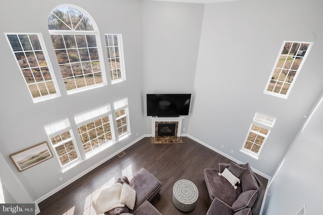 unfurnished living room featuring plenty of natural light, dark wood-type flooring, and a high ceiling