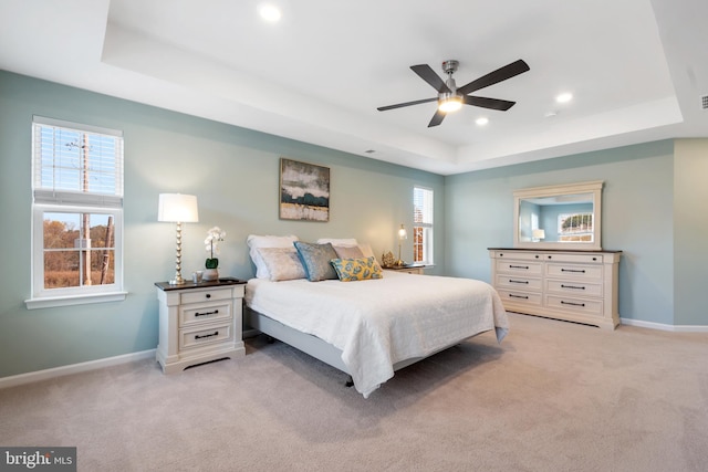 carpeted bedroom with ceiling fan and a raised ceiling