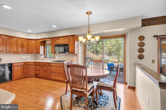 kitchen with black appliances, pendant lighting, a healthy amount of sunlight, and light hardwood / wood-style flooring