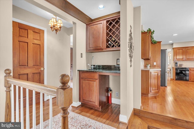 bar with stainless steel fridge, decorative light fixtures, dishwasher, a chandelier, and light hardwood / wood-style flooring