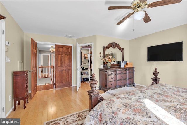 bedroom featuring ceiling fan, a closet, light hardwood / wood-style flooring, and a walk in closet