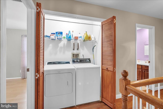 laundry room with light wood-type flooring, sink, and washer and dryer