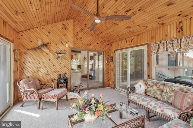 carpeted living room with high vaulted ceiling, wooden walls, wooden ceiling, and ceiling fan