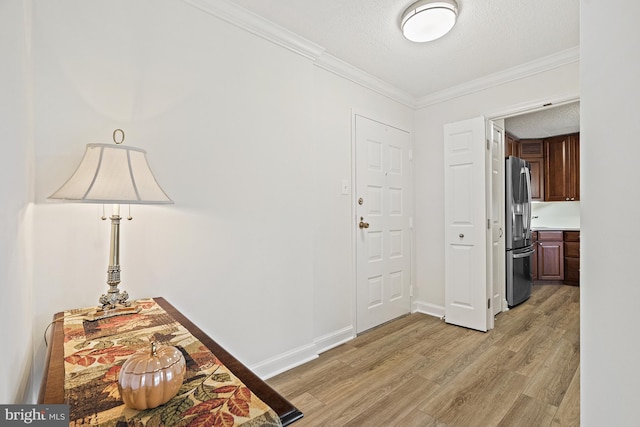 foyer with light hardwood / wood-style floors, a textured ceiling, and ornamental molding