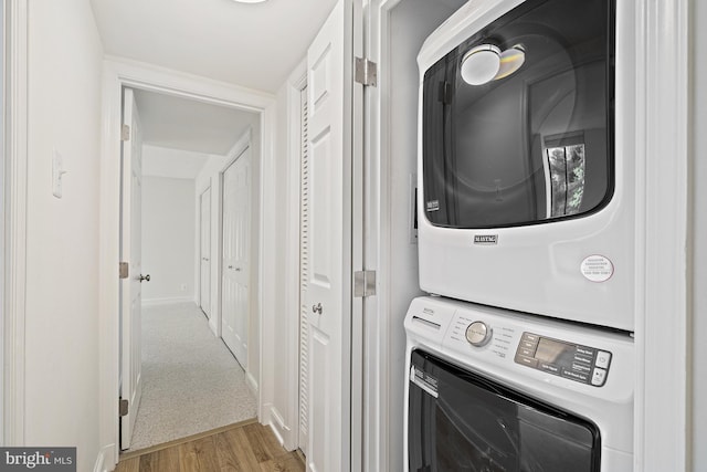 laundry area featuring stacked washer and dryer and light hardwood / wood-style floors