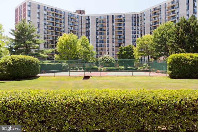 view of home's community featuring a lawn and tennis court