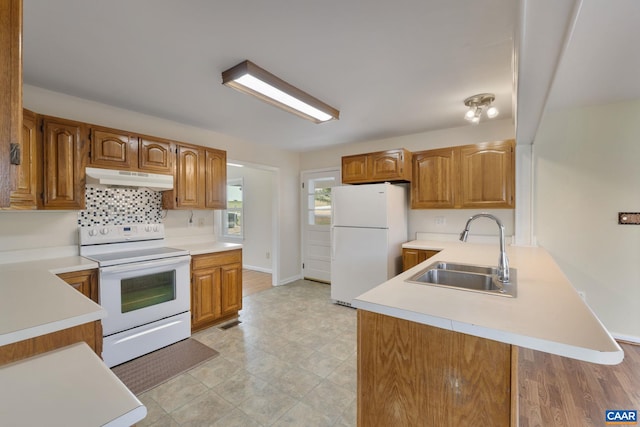 kitchen with tasteful backsplash, kitchen peninsula, white appliances, and sink