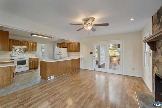 kitchen with white appliances, ceiling fan, light hardwood / wood-style flooring, and kitchen peninsula