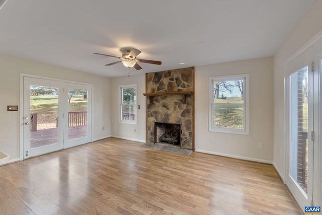 unfurnished living room featuring ceiling fan, a stone fireplace, and light hardwood / wood-style flooring