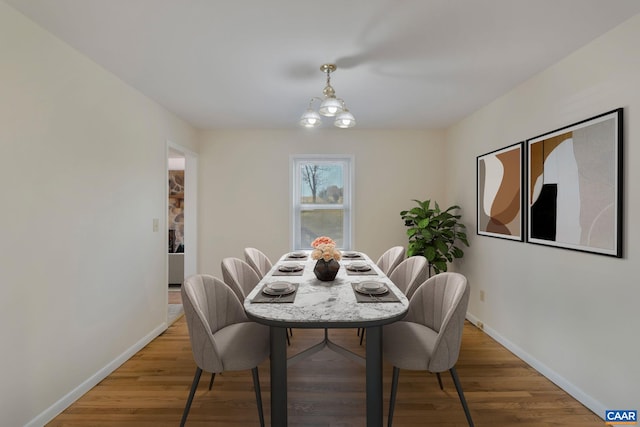 dining space with hardwood / wood-style flooring and an inviting chandelier