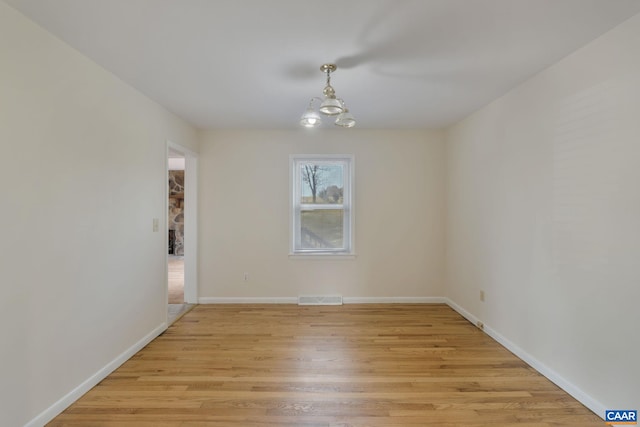 empty room with a chandelier and light hardwood / wood-style floors