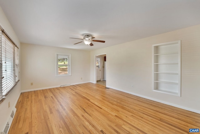 spare room with built in features, ceiling fan, and light hardwood / wood-style floors