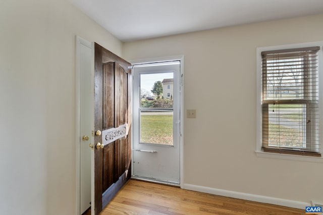 doorway to outside with light wood-type flooring and a wealth of natural light