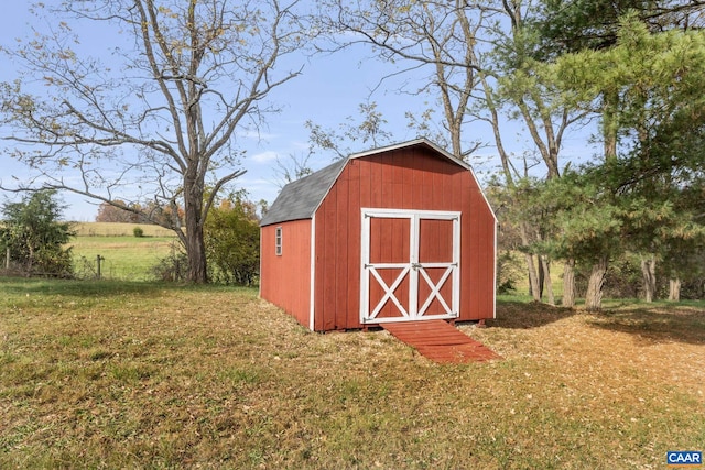 view of outbuilding with a rural view and a yard