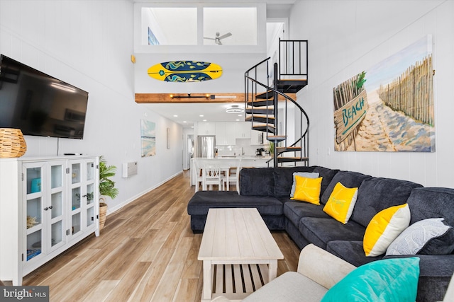 living room featuring light wood-type flooring and a towering ceiling