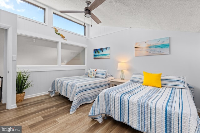 bedroom featuring lofted ceiling, a textured ceiling, ceiling fan, and wood-type flooring