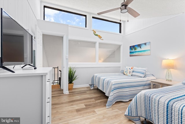 bedroom with ceiling fan, multiple windows, a textured ceiling, and light hardwood / wood-style floors