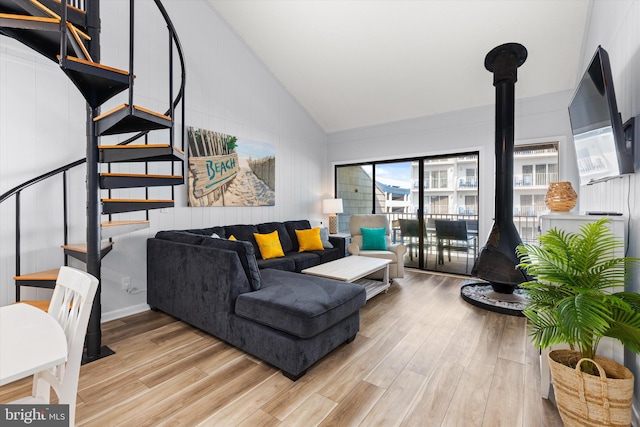 living room with a wood stove, high vaulted ceiling, and light hardwood / wood-style floors