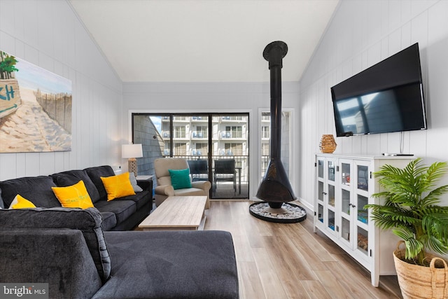 living room with lofted ceiling, a wood stove, and wood-type flooring