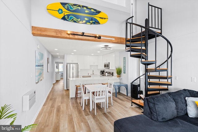 dining space featuring light wood-type flooring, sink, and beam ceiling