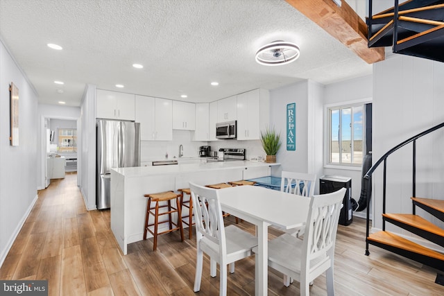 dining space featuring sink, light wood-type flooring, and a textured ceiling