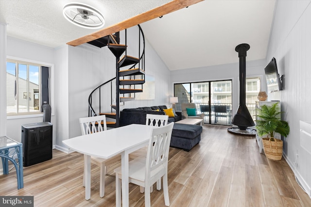 dining space with a textured ceiling, light wood-type flooring, lofted ceiling, and ceiling fan