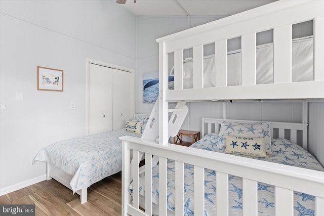 bedroom featuring hardwood / wood-style floors, vaulted ceiling, and a closet