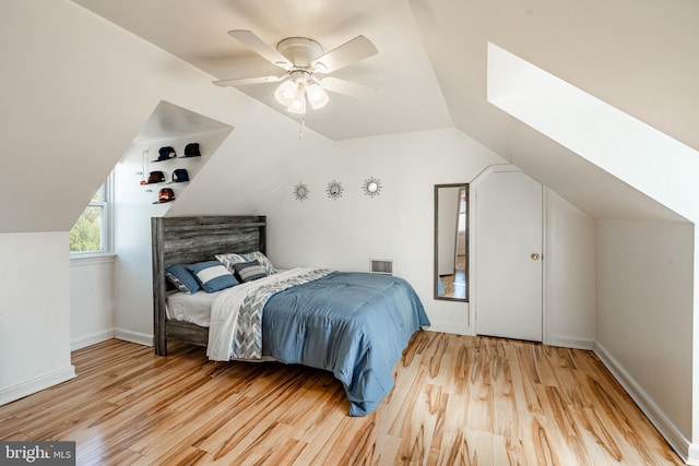 bedroom with ceiling fan, light wood-type flooring, and lofted ceiling with skylight