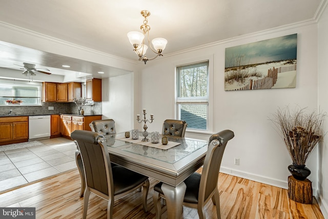 dining space featuring light hardwood / wood-style floors, ceiling fan with notable chandelier, sink, and crown molding