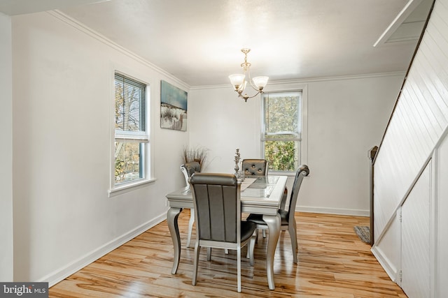 dining space featuring light wood-type flooring, a notable chandelier, and ornamental molding