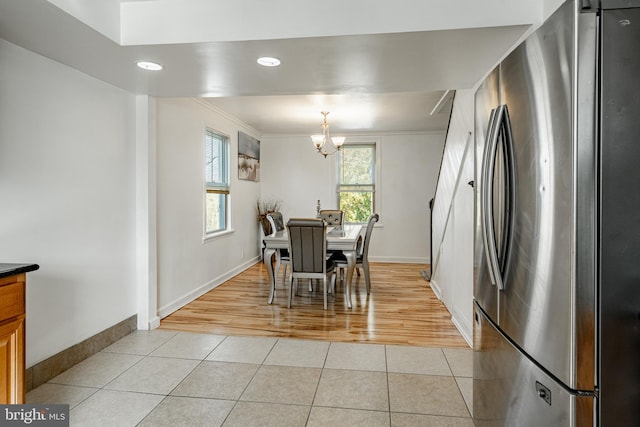 dining space featuring a notable chandelier, ornamental molding, and light hardwood / wood-style flooring