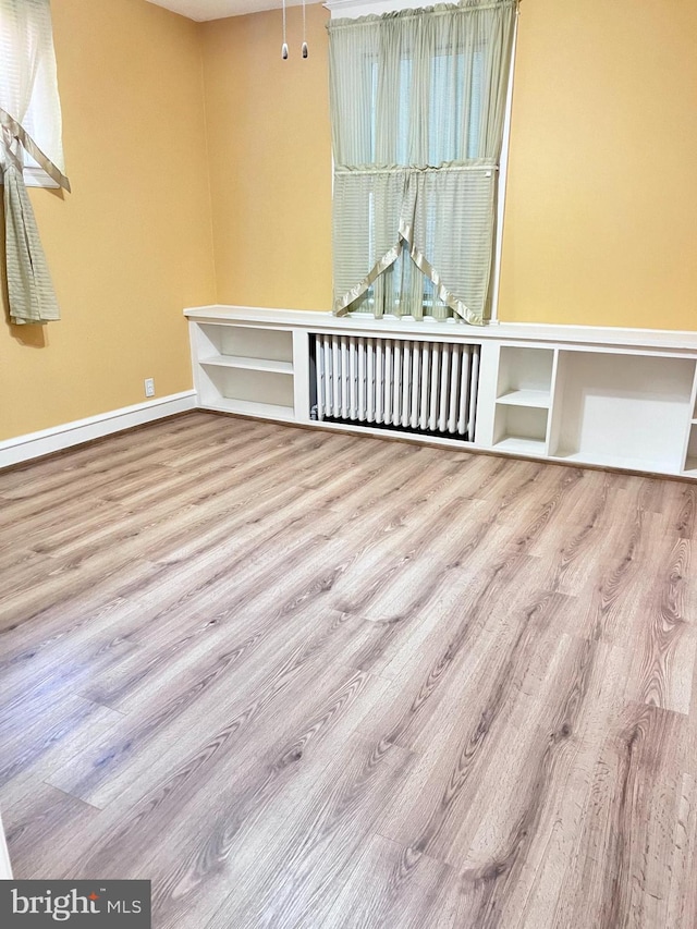 empty room featuring radiator heating unit and light wood-type flooring