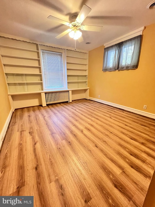 empty room featuring radiator, ceiling fan, and light wood-type flooring